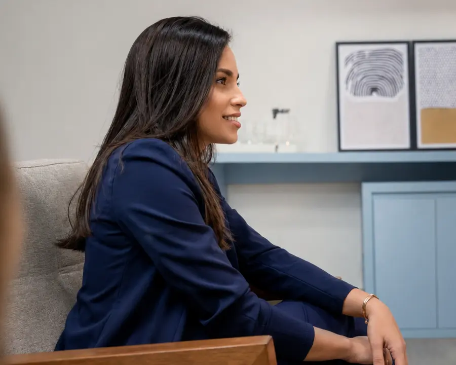 Daniele Ferreira sentada no consultório, de terno azul